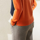 Damenmode: Eleganter, orangefarbener Pullover kombiniert mit grauer Hose. Herbstmode, stilvoller Look, hochwertige Strickwaren.