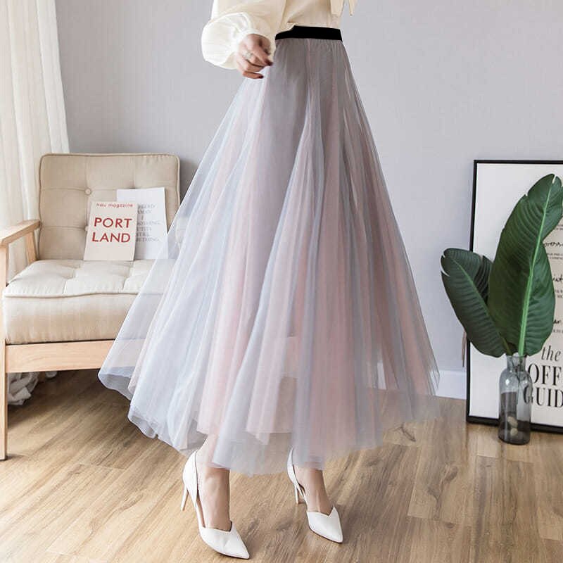 Eleganter langer Tüllrock in Grau, ideal für modische Outfits. Perfekt kombiniert mit weißen High Heels. Damenmode, stilvoll, modern.