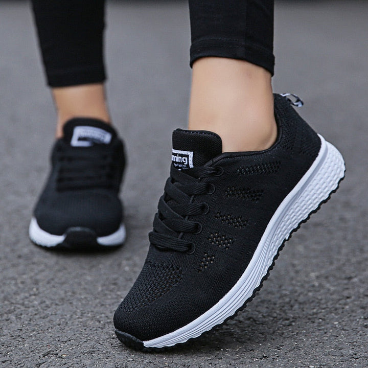 Schwarze Damen-Laufschuhe mit atmungsaktivem Mesh-Obermaterial und weißer Sohle, ideal für Fitness und Freizeit. Bequeme Sportschuhe.
