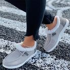Damen-Sneaker mit weißem Kunstfell, grauem Stoff und weißer Sohle. Bequeme, modische Schuhe für Herbst und Winter. Ideal für Freizeitoutfits.