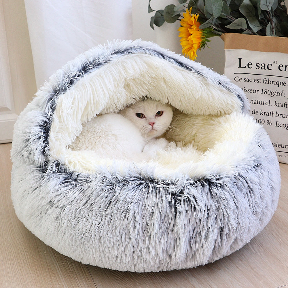 Weiße Katze in flauschigem, grauem Katzenbett mit Sonnenblume im Hintergrund. Gemütliches Haustierbett, ideal für Katzenkomfort und Entspannung.