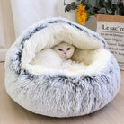 Weiße Katze in flauschigem, grauem Katzenbett mit Sonnenblume im Hintergrund. Gemütliches Haustierbett, ideal für Katzenkomfort und Entspannung.