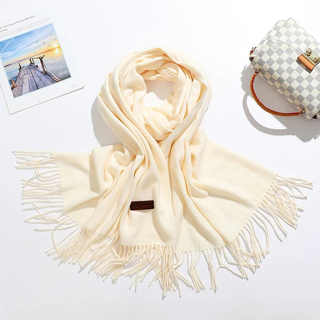 Eleganter cremefarbener Schal mit Fransen, ideal für Herbst und Winter. Weiches Material, modisches Accessoire, perfekt für stilvolle Outfits.