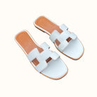 Weiße Ledersandalen mit offenem Zehenbereich und flachem Absatz. Stilvolle Sommerschuhe für Damen, ideal für Freizeit und Strand.