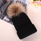 Schwarze Strickmütze mit Kunstfellbommel, modisch und warm, ideal für Wintermode. Perfekt für Damen, die stilvolle Accessoires suchen.