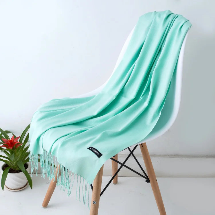 Weicher, mintgrüner Schal auf weißem Stuhl, ideal für stilvolle Herbst- und Wintermode. Perfekt als modisches Accessoire oder Geschenk.