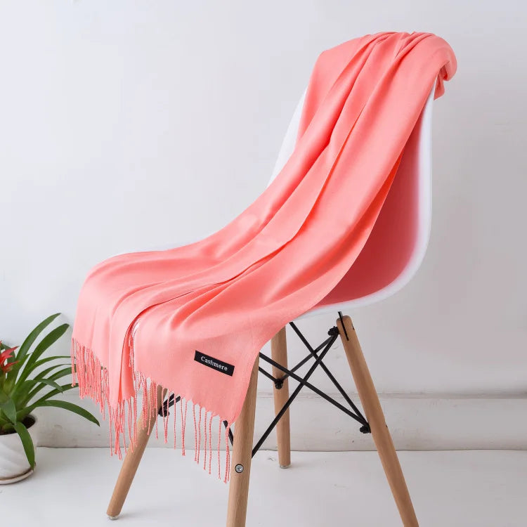 Luxuriöses, rosafarbenes Kaschmirschal auf modernem Stuhl, ideal für stilvolle Wintermode. Weich, elegant und perfekt als Geschenk.