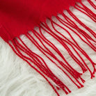 Roter Schal mit Fransen auf weißem Fell. Weicher, warmer Winteraccessoire. Perfekt für kalte Tage. Hochwertige Materialien, modisches Design.