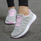 Graue Damen-Laufschuhe mit rosa Schnürsenkeln, atmungsaktivem Mesh-Obermaterial und rutschfester Sohle. Perfekt für Fitness und Freizeit.