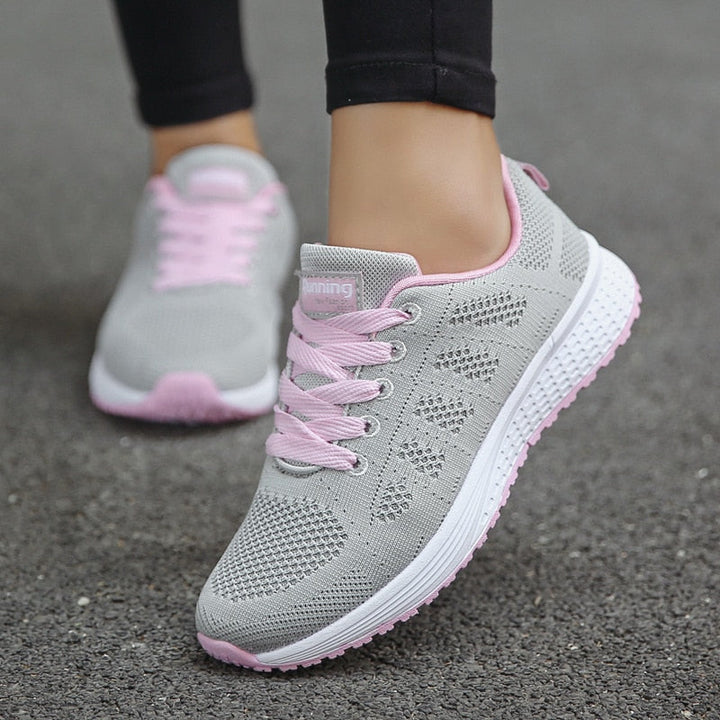 Graue Damen-Laufschuhe mit rosa Schnürsenkeln, atmungsaktivem Mesh-Obermaterial und rutschfester Sohle. Perfekt für Fitness und Freizeit.