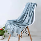 Eleganter hellblauer Schal aus Kaschmir, weich und luxuriös, drapiert über einem modernen Stuhl. Perfekt für stilvolle Herbst- und Wintermode.