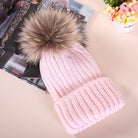 Rosa Strickmütze mit Kunstfellbommel, modisch und warm, ideal für Wintermode. Perfekt für Damen, die stilvolle Accessoires suchen.
