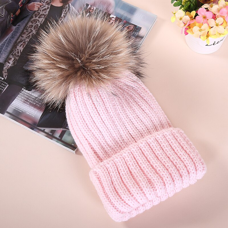 Rosa Strickmütze mit Kunstfellbommel, modisch und warm, ideal für Wintermode. Perfekt für Damen, die stilvolle Accessoires suchen.