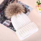 Weiße Strickmütze mit Kunstfellbommel, modisch und warm, ideal für Wintermode. Perfekt für Damen, die stilvolle Accessoires suchen.
