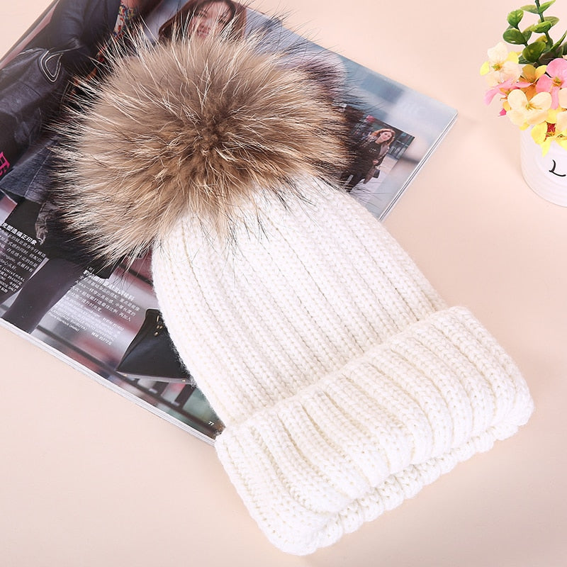Weiße Strickmütze mit Kunstfellbommel, modisch und warm, ideal für Wintermode. Perfekt für Damen, die stilvolle Accessoires suchen.