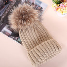Beige Strickmütze mit Kunstfellbommel, modisch und warm, ideal für Wintermode. Perfekt für Damen, die stilvolle Accessoires suchen.