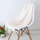 Luxuriöser weißer Kaschmirschal auf modernem Stuhl, ideal für stilvolle Wintermode. Weich, elegant, hochwertig. Perfekt für Damenaccessoires.