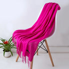 Leuchtend pinker Schal aus weichem Stoff auf modernem Stuhl, ideal für stilvolle Herbst- und Wintermode. Perfekt als modisches Accessoire.
