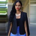 Elegante Frau in schwarzem Blazer und blauer Jeans, mit auffälligem Schmuck. Mode, Damenbekleidung, stilvoll, modern, urbaner Look.
