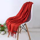 Weicher roter Kaschmirschal auf weißem Stuhl, ideal für stilvolle Herbst- und Wintermode. Luxuriöses Accessoire, warm und elegant.