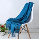 Luxuriöser blauer Kaschmirschal auf weißem Stuhl, ideal für stilvolle Wintermode. Weich, warm und elegant. Perfekt für Damen und Herren.