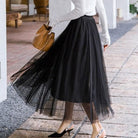 Eleganter schwarzer Tüllrock kombiniert mit weißen Pumps und brauner Handtasche. Perfekt für stilvolle Damenmode und trendige Outfits.