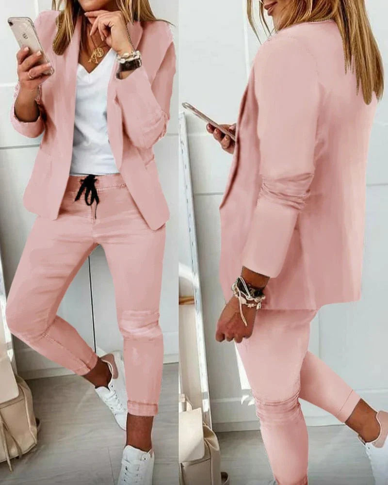 Damenanzug in Rosa, bestehend aus Blazer und Hose, kombiniert mit weißem T-Shirt und Sneakers. Modisch, elegant, ideal für Business und Freizeit.