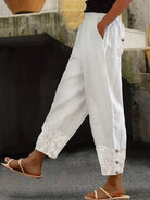 Damenhose aus Leinen in Weiß mit floralen Stickereien, Knopfleiste und Seitentaschen. Perfekt für Sommermode und lässige Outfits.