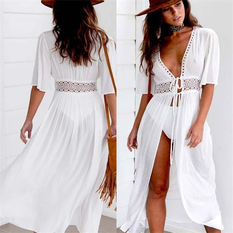 Weißes Strandkleid mit Spitzen-Details, tiefem V-Ausschnitt und Fransen-Tasche. Perfekt für Sommer, Strandmode und Boho-Stil.