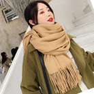 Frau mit beigem Schal und olivgrünem Mantel auf Treppe. Modetrend, Wintermode, stilvoller Look, Damenbekleidung, Accessoires.