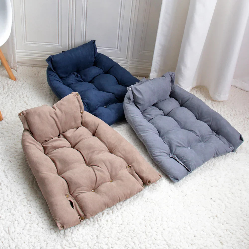 Drei gepolsterte Hundebetten in Blau, Grau und Beige auf weißem Teppich.