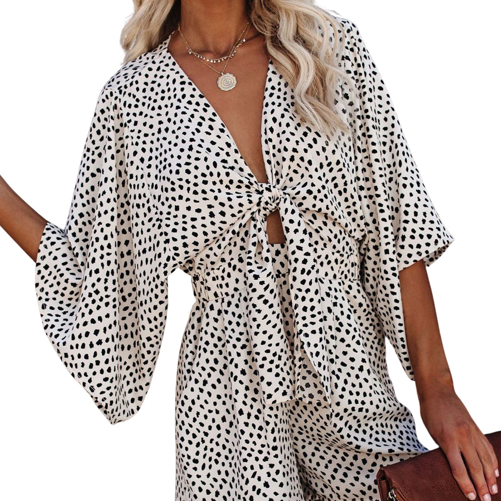 Damen Sommerkleid mit schwarz-weißem Tupfenmuster, V-Ausschnitt und Knoten-Detail. Perfekt für Freizeitmode und trendige Outfits.