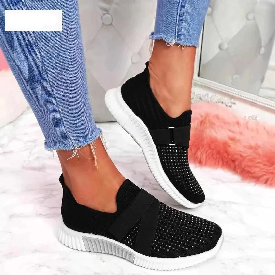 Schwarze Damen-Sneaker mit Strass, elastisch, bequem, modisch, auf rosa Teppich.