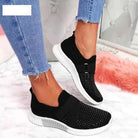 Schwarze Damen-Sneaker mit Strass, elastisch, bequem, modisch, auf rosa Teppich.