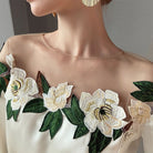 Elegantes Damenkleid mit floralen Stickereien, transparentem Ausschnitt und goldenen Ohrringen. Perfekt für besondere Anlässe und modische Events.