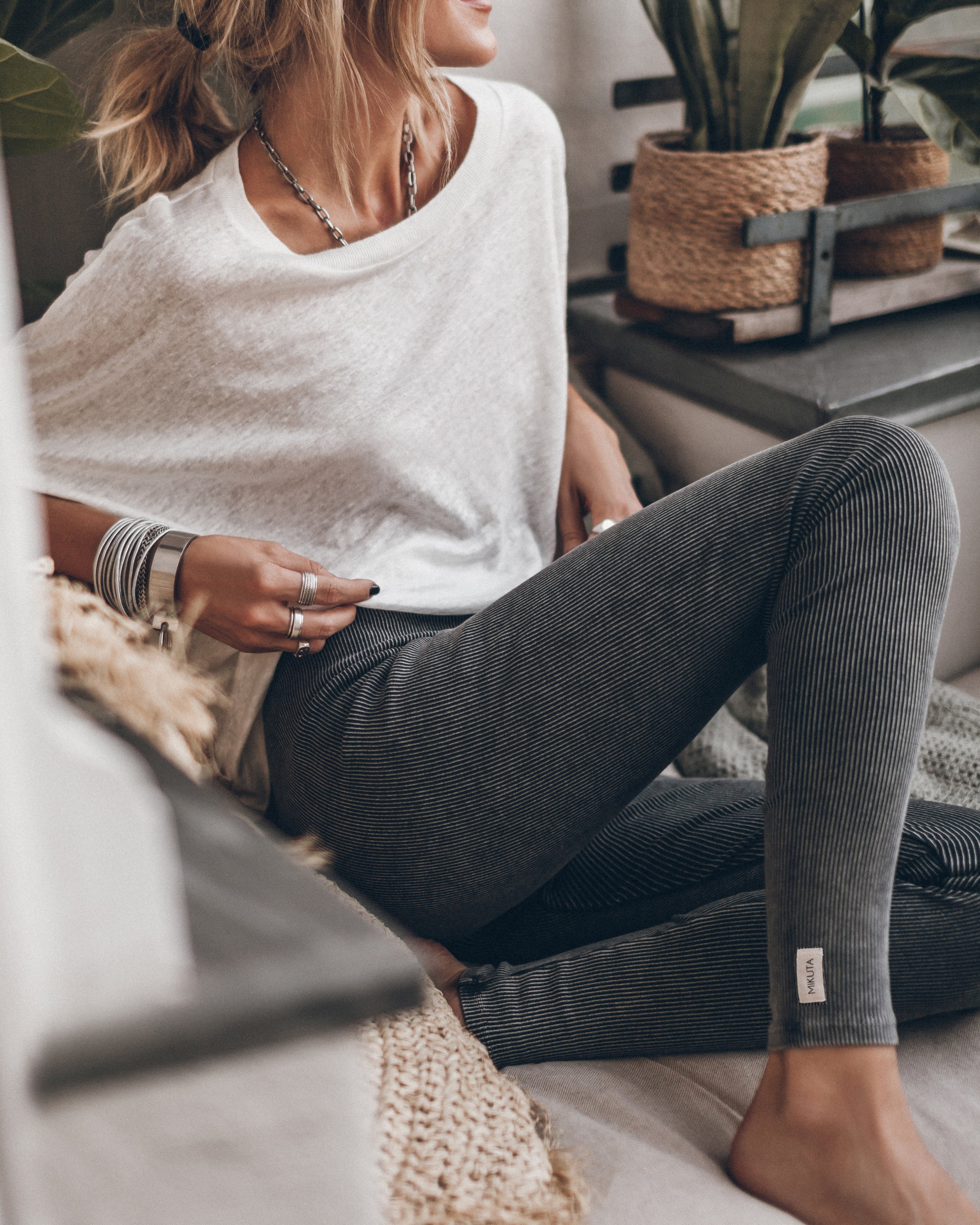 Frau in gemütlicher Kleidung: Weißes Shirt, graue Leggings. Perfekt für entspannte Tage zu Hause. Modetrend, Komfort, Freizeitkleidung.