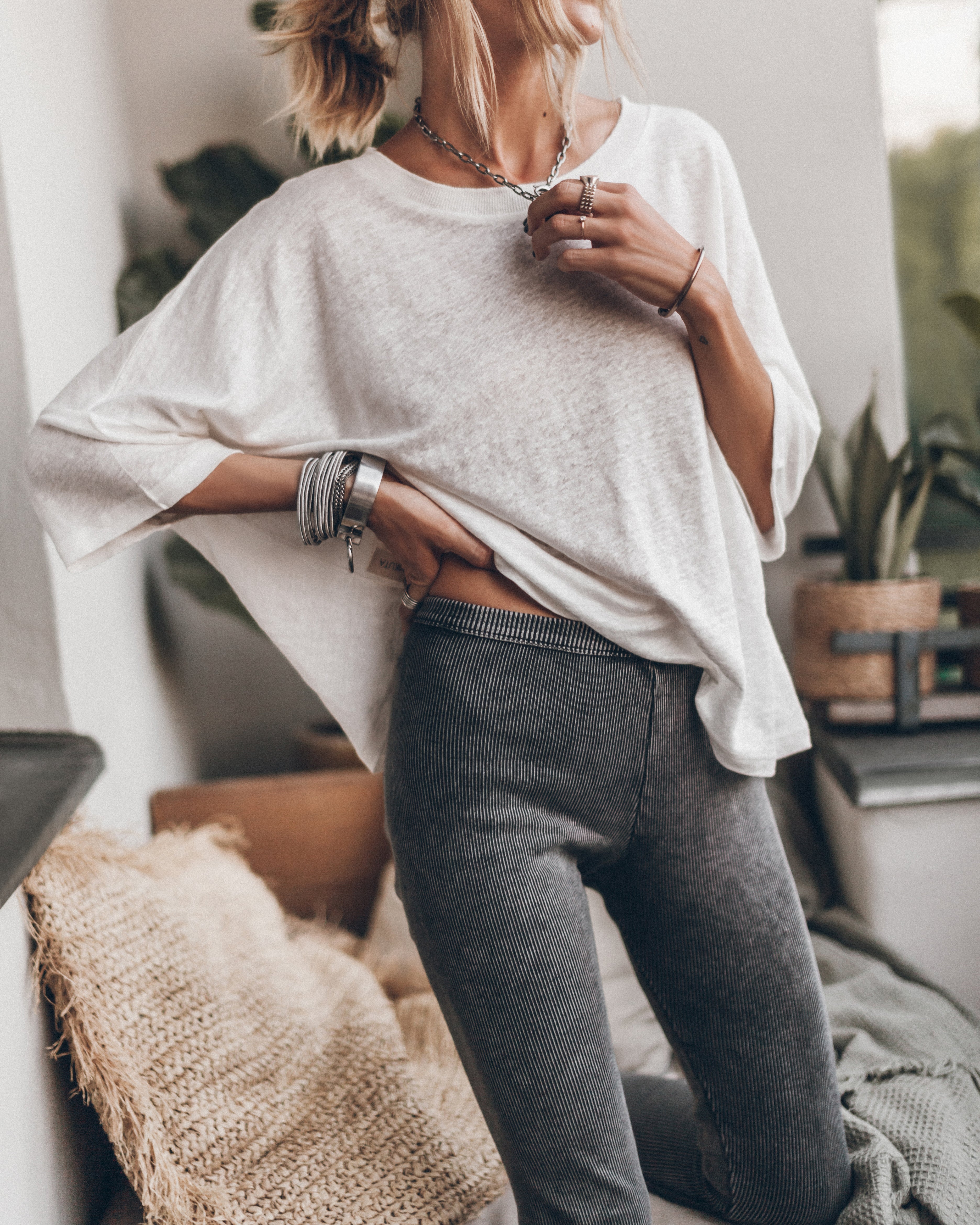 Frau in lässigem Outfit: Weißes Oversize-Shirt, graue Leggings, Schmuck. Perfekt für entspannte Mode, Casual-Look, Streetstyle.