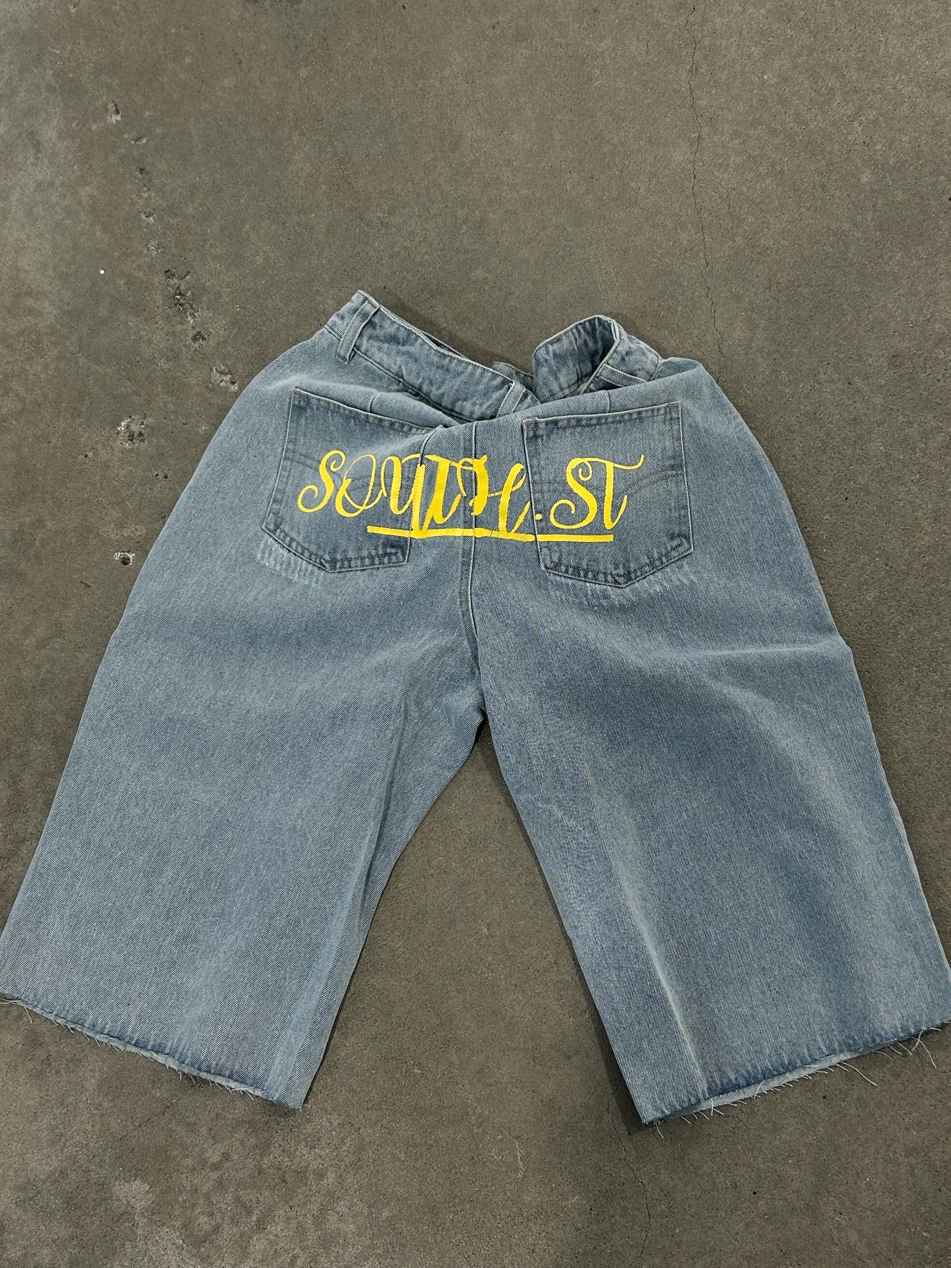Graue Jeans-Shorts mit gelbem "SOWE4ST"-Schriftzug auf den Gesäßtaschen, lässiger Stil, ideal für Streetwear und Sommermode.