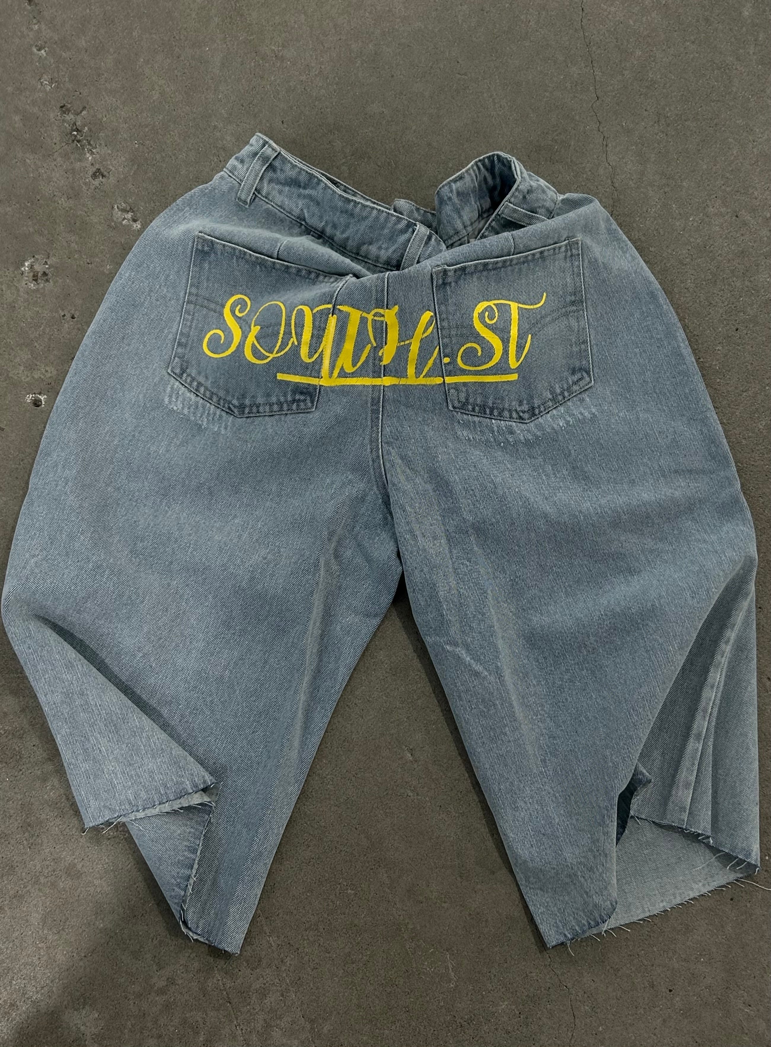 Graue Jeans mit gelbem "SOWELT"-Schriftzug auf den Gesäßtaschen, lässiger Stil, modische Streetwear, ideal für trendige Outfits.