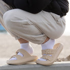 Beige Sandalen mit zwei Schnallen, getragen mit weißen Socken. Komfortable Sommerschuhe, ideal für Strand und Freizeit. Trendige Modeaccessoires.