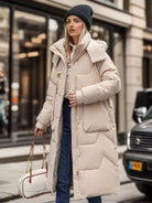 Frau in beigem Daunenmantel, Wintermode, stilvoll, warm, mit Mütze und Tasche, städtische Umgebung, modische Damenbekleidung, Outdoor-Look.