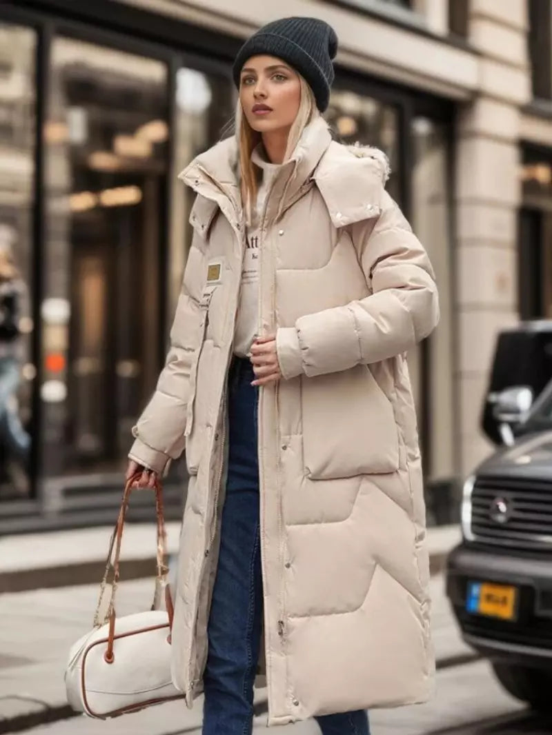 Frau in beigem Daunenmantel, Wintermode, stilvoll, warm, mit Mütze und Tasche, städtische Umgebung, modische Damenbekleidung, Outdoor-Look.