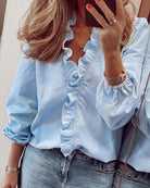 Frau in hellblauer Rüschenbluse und Jeans, Spiegel-Selfie, modische Damenbekleidung.