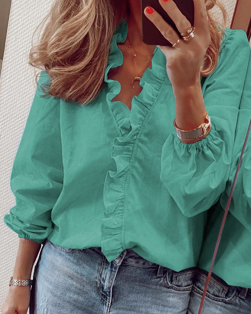 Frau in türkisfarbener Rüschenbluse und Jeans, Spiegel-Selfie, modische Damenbekleidung.