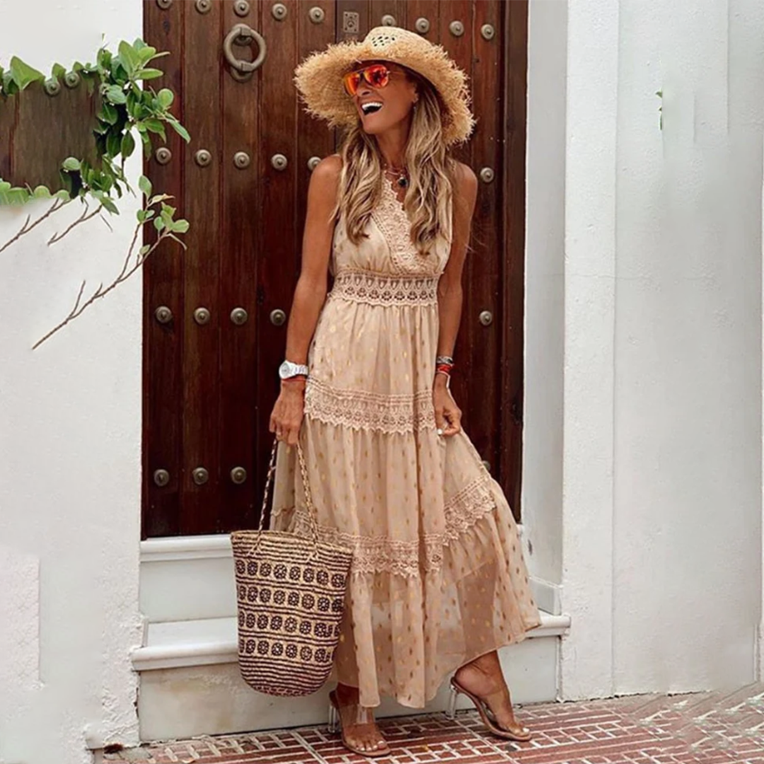 Frau in langem, khakifarbenem Sommerkleid mit Strohhut und Korbtasche vor Holztür. Perfekter Boho-Look für den Sommer.
