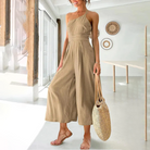 Frau in khaki Jumpsuit mit Strohtasche, Sommermode, elegantes Design, helle Umgebung.