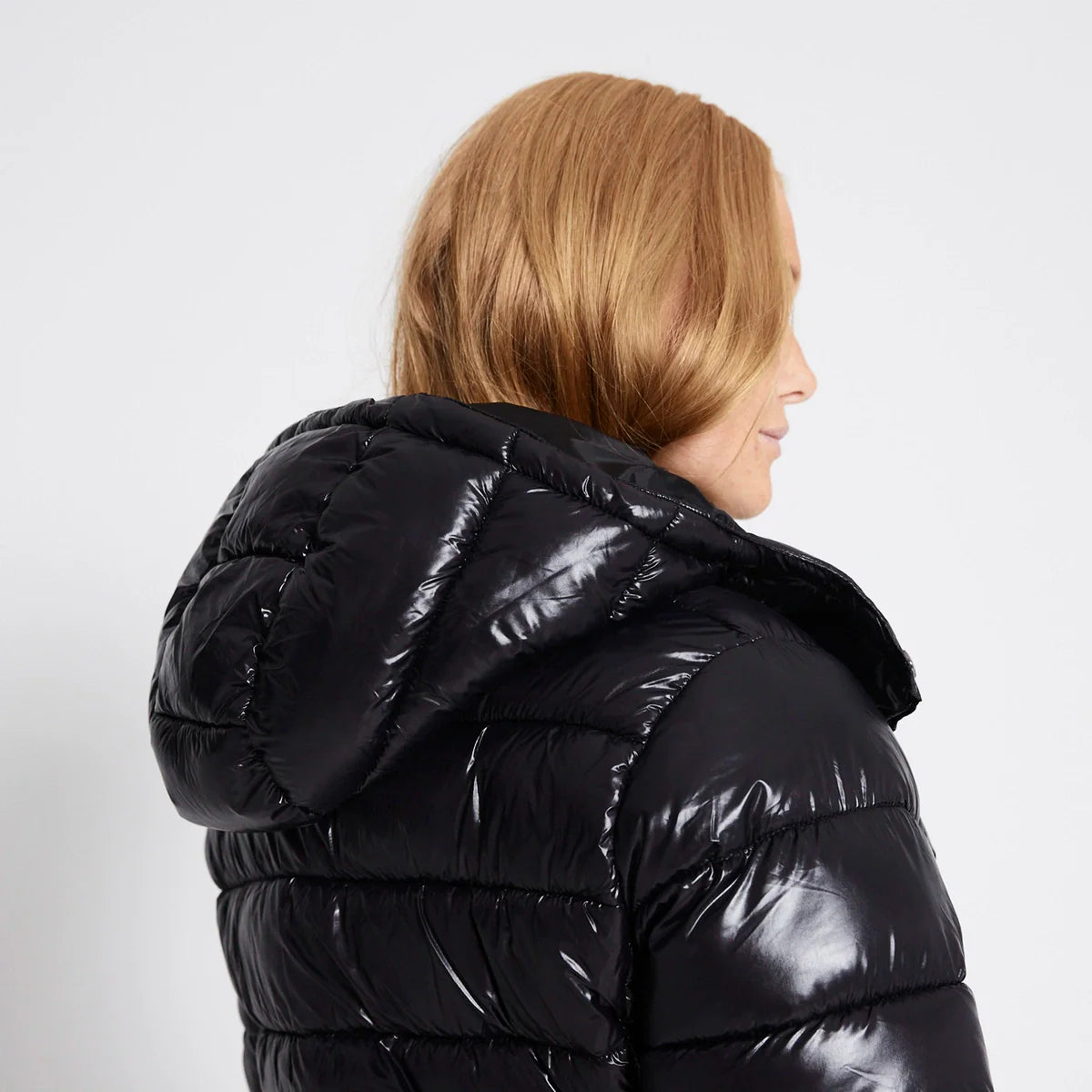 Schwarze, glänzende Pufferjacke mit Kapuze, ideal für kalte Wintertage. Modische Damenjacke, warm und stilvoll, perfekt für Outdoor-Aktivitäten.