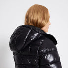 Schwarze, glänzende Pufferjacke mit Kapuze, ideal für kalte Wintertage. Modische Damenjacke, warm und stilvoll, perfekt für Outdoor-Aktivitäten.