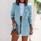 Damenmode: Hellblauer Blazer, Slim Fit, mit doppelter Knopfleiste, kombiniert mit weißem Crop-Top und Jeansshorts. Eleganter, lässiger Look.