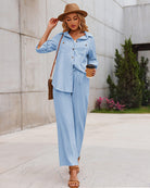 Frau in hellblauem Freizeitanzug mit Kaffeebecher, Strohhut und Sandalen. Modetrend, Damenbekleidung, lässiger Stil, Sommeroutfit.